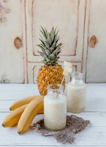 Batido de frutas ecológicas con plátanos y piña sobre fondo blanco - foto de stock