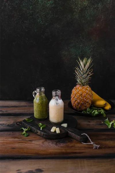 Delicious detox smoothies with tropical fruits on rustic wooden board — Stock Photo