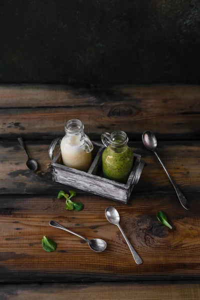 Frische gesunde grüne und weiße Smoothies auf rustikalem Tisch — Stockfoto