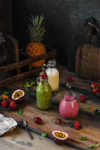 Delicious detox smoothies in bottles on rustic wooden board — Stock Photo