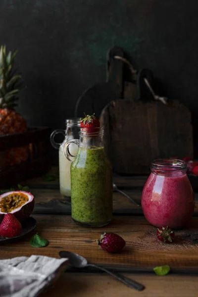 Deliciosos batidos de desintoxicación sobre tabla de madera rústica con bayas y frutas - foto de stock