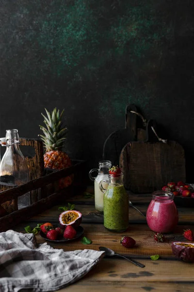 Batidos de frutas ecológicas con frutas en desorden sobre fondo de madera - foto de stock