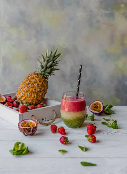 Organic layered fruit smoothie on wooden background with exotic fruits — Stock Photo