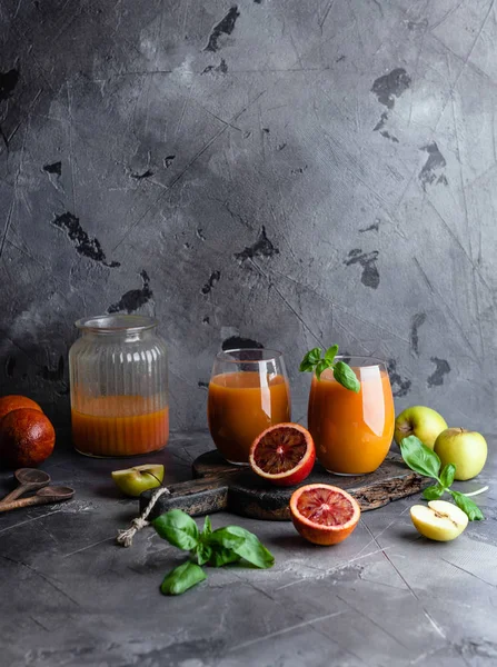 Batido de frutas ecológicas sobre fondo de madera con naranjas y manzanas - foto de stock