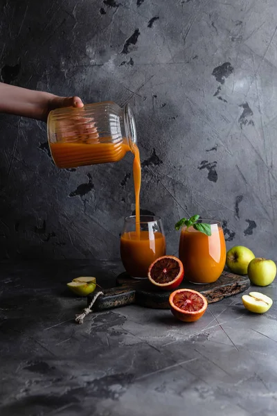 Mano femenina vertiendo batido saludable de tarro en vidrio sobre mesa rústica - foto de stock