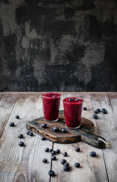 Délicieux smoothie aux baies dans des verres sur une planche en bois rustique — Photo de stock