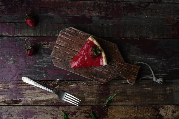 Vista superior del pedazo de pastel de fresa y tenedor en la mesa de madera - foto de stock