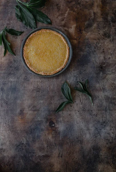 Vue de dessus de tarte au citron savoureuse et feuilles sur table en bois — Photo de stock