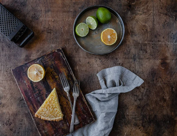 Top view of tasty lemon pie on cutting board and fruits on plate — Stock Photo