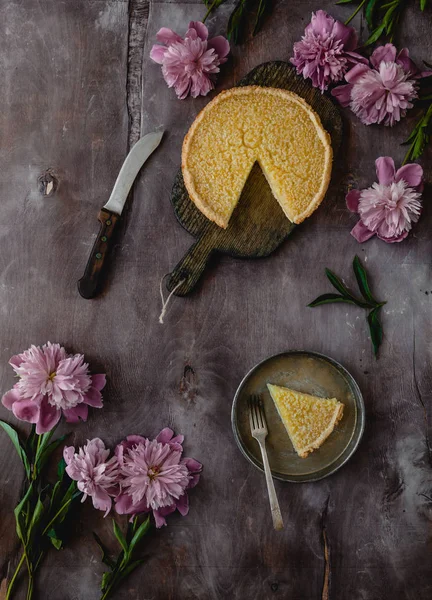 Vue de dessus de tarte au citron savoureuse sur table en bois avec pivoines violettes — Photo de stock