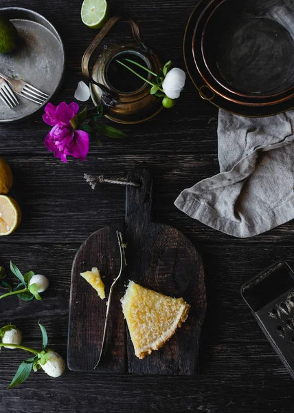 Vista elevada de pedaço de torta de limão saboroso e flores na mesa de madeira — Fotografia de Stock