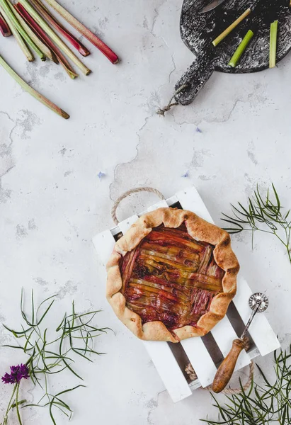 Vue du dessus de délicieuse tarte à la rhubarbe et des brindilles éparses sur la table — Photo de stock