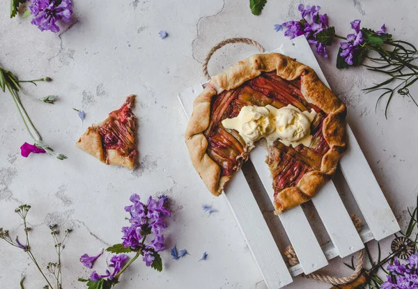 Vista elevada de deliciosa torta de ruibarbo na mesa com flores violetas — Fotografia de Stock