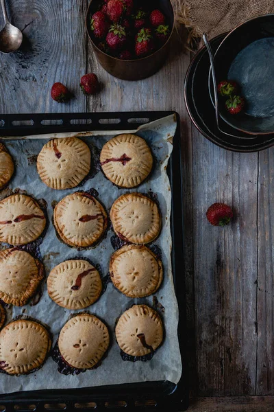 Erhöhter Blick auf gekochte leckere Plätzchen mit Erdbeeren auf Tablett — Stockfoto