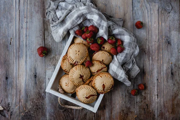 Vista elevada de sabrosas galletas con fresas en bandeja sobre mesa de madera - foto de stock