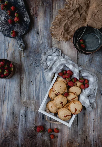 Elevated view of tasty cookies with strawberries in tray on wooden table — Stock Photo