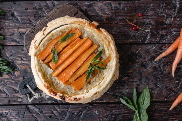 Vista sopraelevata di deliziosa torta con carote ed erbe sul tavolo di legno — Foto stock