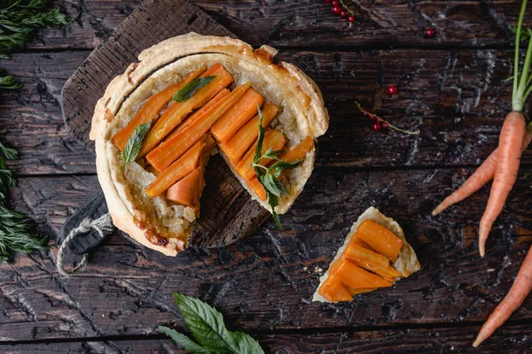 Vista elevata di torta saporita con carote ed erbe su tavolo di legno — Foto stock