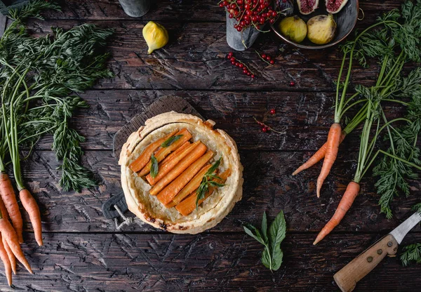 Top view of tasty pie with carrots and herbs on wooden table — Stock Photo