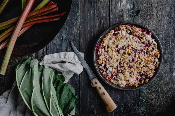 Erhöhter Blick auf leckere Torte mit Beeren und Rhabarber auf Holztisch — Stockfoto