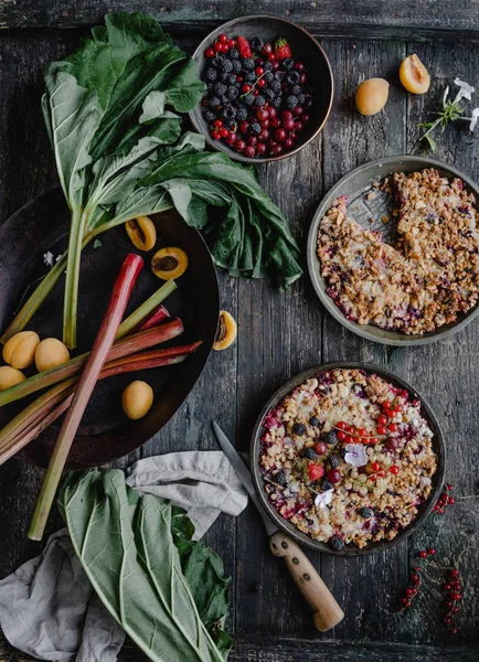 Vue surélevée de savoureuses tartes aux baies et à la rhubarbe sur table en bois — Photo de stock