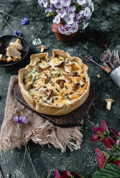 Аппетитный пирог с грибами и цветами в горшках на деревянном столе — стоковое фото