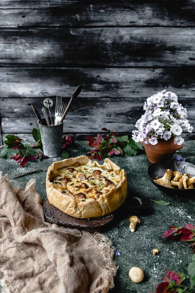 Tasty pie with mushrooms and potted flowers on wooden table — Stock Photo