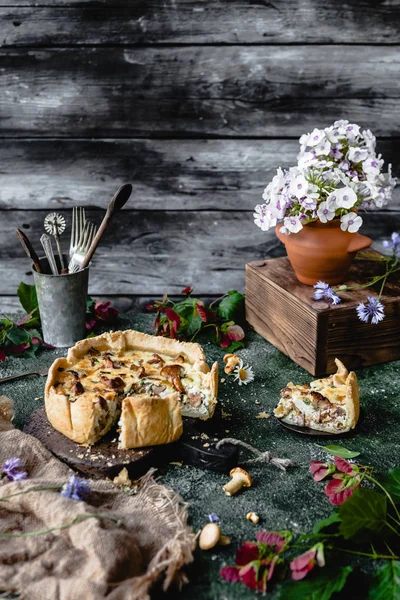 Torta gustosa con funghi e fiori in vaso sul tavolo di legno — Foto stock