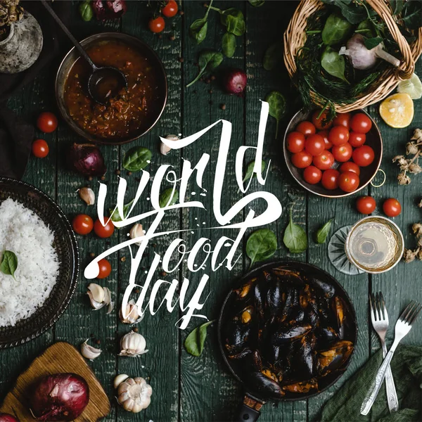 Draufsicht auf gekochte Muscheln mit Schalen, serviert in Pfanne mit Tomaten, Kräutern und Wein auf Holztisch, Schriftzug zum Welternährungstag — Stockfoto