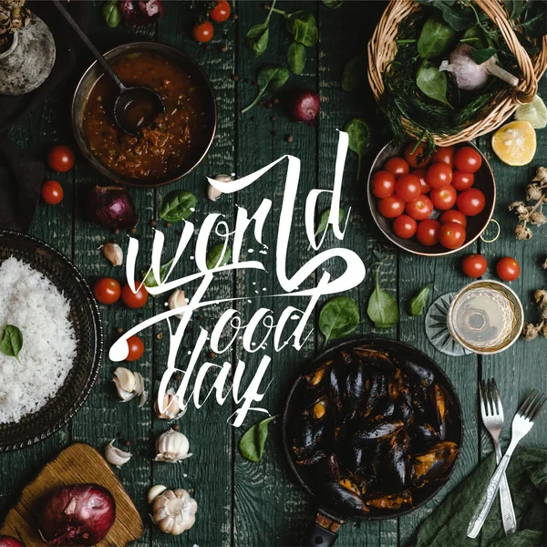 Top view of cooked mussels with shells served in pan with tomatoes, herbs and wine on wooden table, world food day lettering — Stock Photo