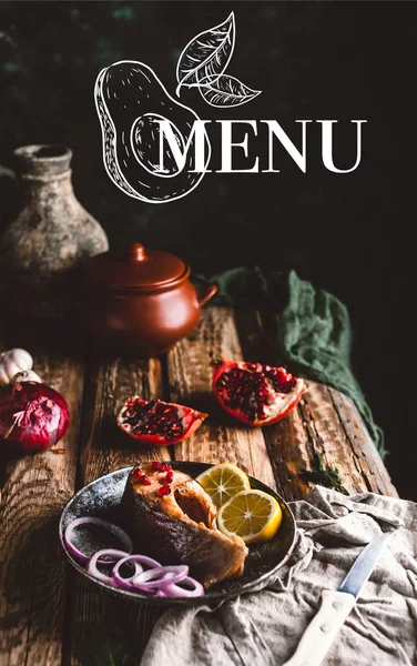 Baked salmon steak with lemon and onion on plate with pomegranate on wooden table, menu lettering — Stock Photo