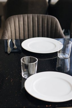 Beyaz tabaklar, gözlük ve siyah tablo, zarif sofra gereçleri 