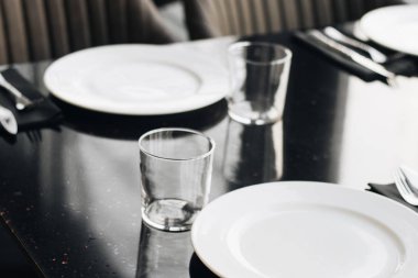 Beyaz tabaklar, gözlük ve siyah tablo, zarif sofra gereçleri 