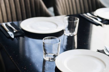 Beyaz tabaklar, gözlük ve siyah tablo, zarif sofra gereçleri 