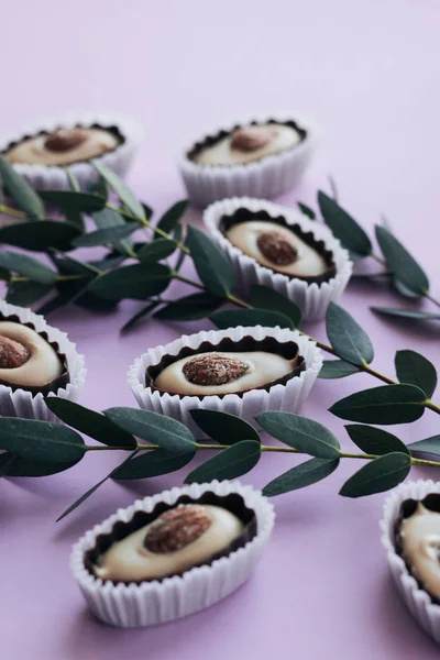 Composição Deliciosos Doces Pralinos Com Amêndoas Galhos Verdes Fundo Roxo — Fotografia de Stock