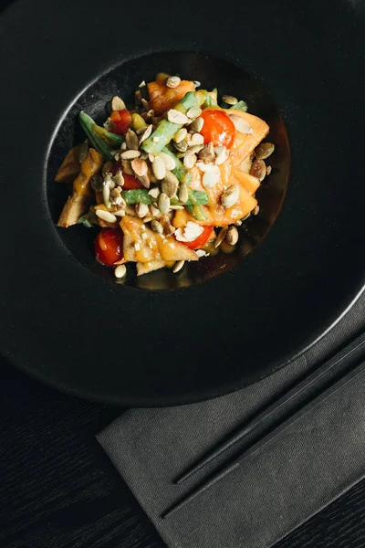 fresh healthy dinner with seeds and vegetables on black plate