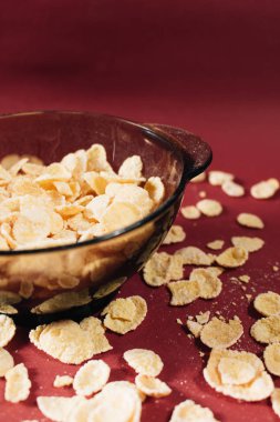 Kırmızı arka planda kasede mısır gevreği ve sağlıklı bir kahvaltı.