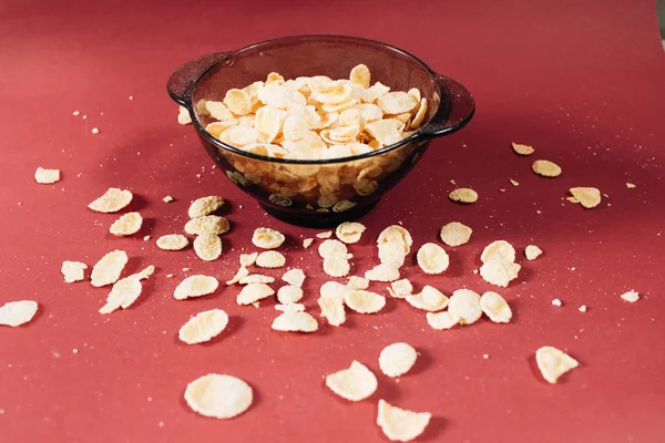 Kırmızı arka planda kasede mısır gevreği ve sağlıklı bir kahvaltı.