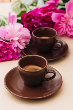 kahve ve pembe şakayık çiçekleri arka plan üzerinde kahverengi su bardağı