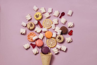 lezzetli tatlı şekerleme ve Lila arka plan üzerinde renkli macaroons ve düz lay