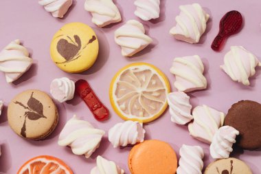 lezzetli tatlı şekerleme ve Lila arka plan üzerinde renkli macaroons ve düz lay