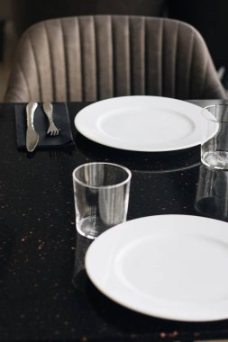Beyaz tabaklar, gözlük ve siyah tablo, zarif sofra gereçleri 