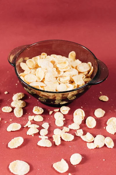 Kırmızı arka planda kasede mısır gevreği ve sağlıklı bir kahvaltı.