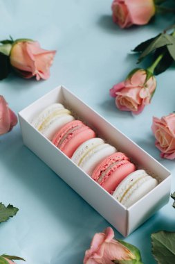 bileşimi lezzetli macaroons ve mavi masada pembe güller