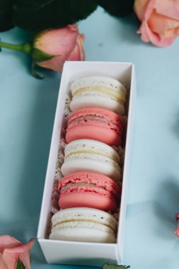 bileşimi lezzetli macaroons ve mavi masada pembe güller