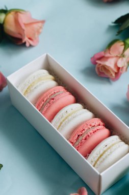 bileşimi lezzetli macaroons ve mavi masada pembe güller