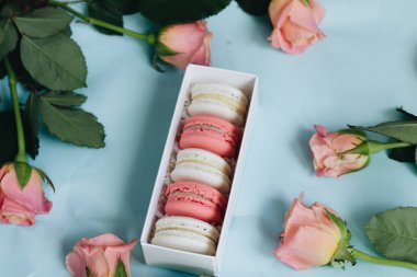 bileşimi lezzetli macaroons ve mavi masada pembe güller