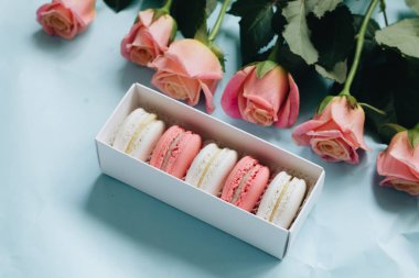 bileşimi lezzetli macaroons ve mavi masada pembe güller