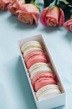 bileşimi lezzetli macaroons ve mavi masada pembe güller