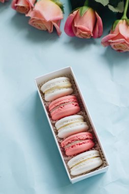 bileşimi lezzetli macaroons ve mavi masada pembe güller